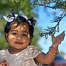 child, toddler, girl, pigtails, bows, white_dress, lace, bracelet, outdoor, tree_branch, leaf, sunlight, shadow, blue_sky, portrait, smile, cute, face, hand, daylight