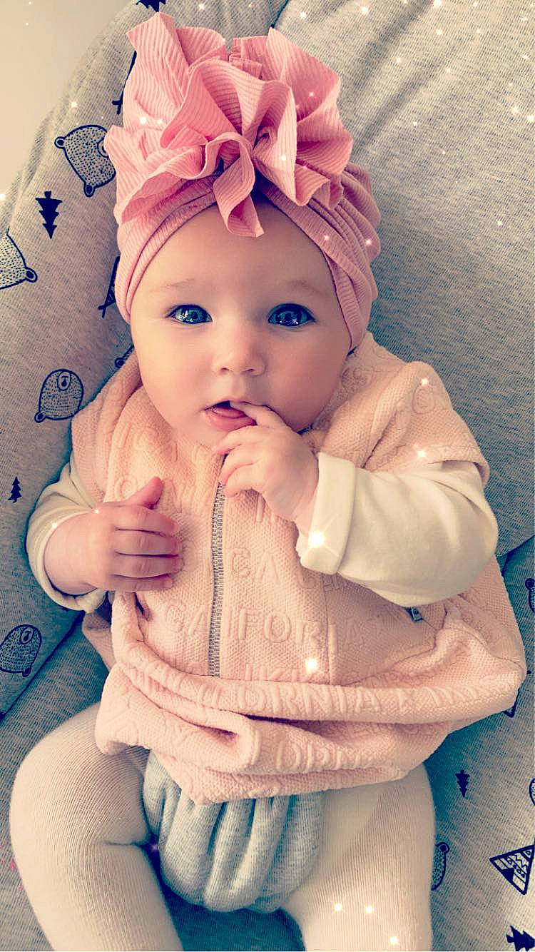 Livia a rejoint le concours — aidez-le/la à gagner de superbes lots ! baby, baby_toddler_clothing, cap, cheek, chin, eye, face, head, headgear, headwear, human_body, iris, lip, mouth, neck, person, pink, purple, skin, sleeve