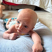 Noha a rejoint le concours — aidez-le/la à gagner de superbes lots ! arm, baby, bed, blue_eyes, curious, cushion, cute, diaper, expression, floor, head, indoors, infant, lying_down, necklace, person, skin, small_hand, soft_texture, toddler