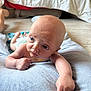 arm, baby, bed, blue_eyes, curious, cushion, cute, diaper, expression, floor, head, indoors, infant, lying_down, necklace, person, skin, small_hand, soft_texture, toddler
