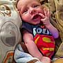 Conrad joined the competition — help win amazing prizes! baby, infant, blanket, superman_logo, clothing, face, hand, smiling, happy, cuddly, soft_texture, toddler, cute, indoors, portrait, expression, playful, wrapped, cozy, child