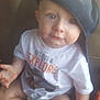 Conrad is registered to the contest to win money with this photo: baby, child, cap, hat, tshirt, sitting, indoor, furniture, curious, cute, person, face, clothing, blue, white, young, infant, headwear, expression, soft
