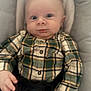 baby, infant, child, plaid_shirt, button_up_shirt, car_seat, buckle, hands, wide_eyes, surprised_expression, chubby_cheeks, face, portrait, indoor, blanket, head_support, seatbelt, skin, newborn, soft_lighting
