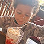 Victor joined the competition — help win amazing prizes! child, curly_hair, dessert, whipped_cream, glass, spoon, table, cafe, window, natural_light, food, happy, eating, indoor, person, seat, clothing, face, mouth, curly