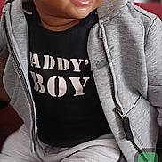 Moses is registered to the contest to win money with this photo: toddler, child, smiling, hoodie, pants, sitting, shoes, indoor, portrait, cute, happy, face, person, clothing, baby, casual, expression, young_child, sweatshirt, playful