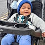 Moses joined the competition — help win amazing prizes! toddler, child, stroller, sweater, hat, pom_pom, shoes, baby_shoes, blue_pants, smile, outdoor, sidewalk, gray_sky, seatbelt, graco, footwear, cute, happy, person, casual_clothing