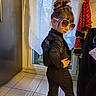 Lucia a rejoint le concours — aidez-le/la à gagner de superbes lots ! child, indoor, pose, sunglasses, black_clothing, hair_bun, window, curtains, tiled_floor, standing, fashion, confident, casual, home, person, clothing, accessories, colorful, playful, young