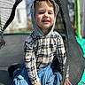 Eli joined the competition — help win amazing prizes! child, boy, hoodie, plaid_shirt, jeans, trampoline, netting, outdoor, daylight, smile, kneeling, casual_clothing, blue_eyes, blond_hair, play, safety_net, background_blur, person, happy, fun
