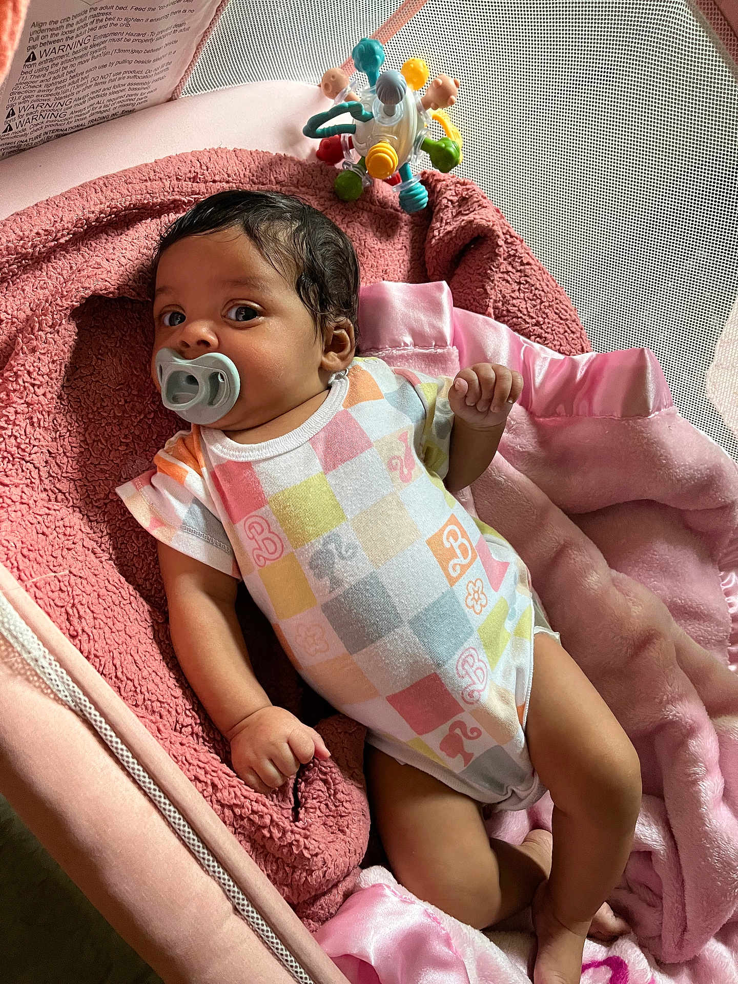 Cherish is registered to the contest to win money with this photo: baby, pacifier, blanket, onesie, infant, soft_toy, pink, cute, lying_down, indoor, child, newborn, playpen, colorful, cozy, portrait, baby_clothing, relaxed, toy, resting
