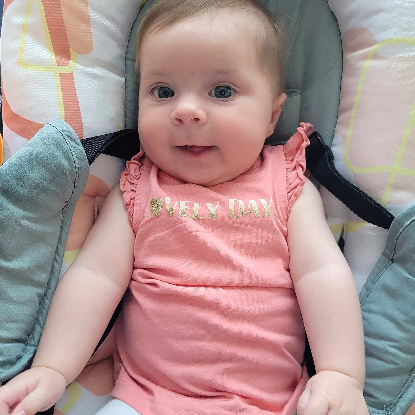 Rose participe au concours pour gagner de l'argent avec cette photo : baby, baby_chair, baby_girl, blue_eyes, child, cushion, cute, face, hands, happy, indoors, infant, pink_clothing, portrait, seated, skin, smile, soft_lighting, text_on_clothing, white_pants