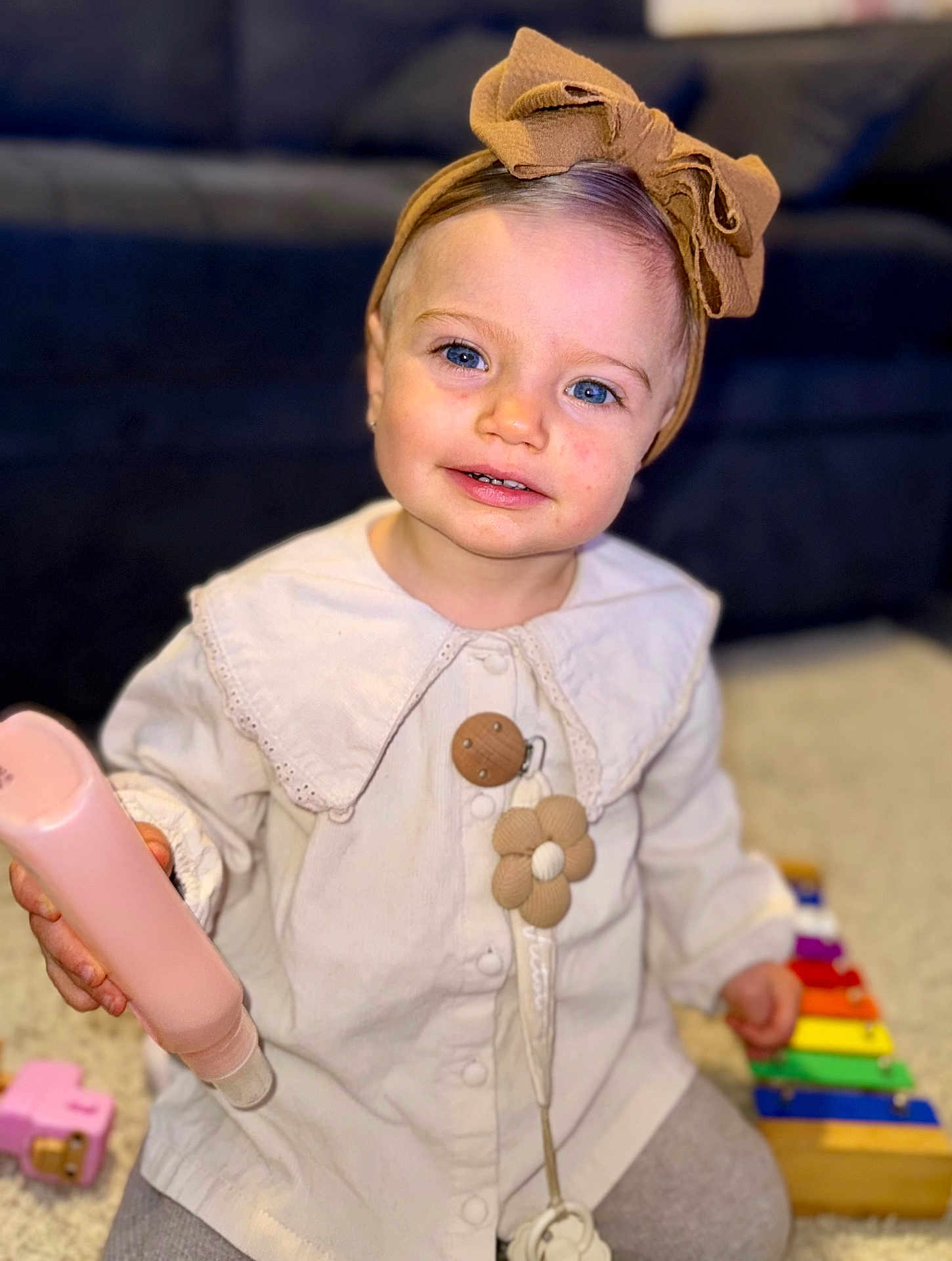 Victoire a rejoint le concours — aidez-le/la à gagner de superbes lots ! baby, blue_eyes, bow, carpet, child, clothing, cute, happy, headband, indoor, pacifier_clip, person, pink_bottle, playing, portrait, smile, toddler, toy, xylophone, young_child