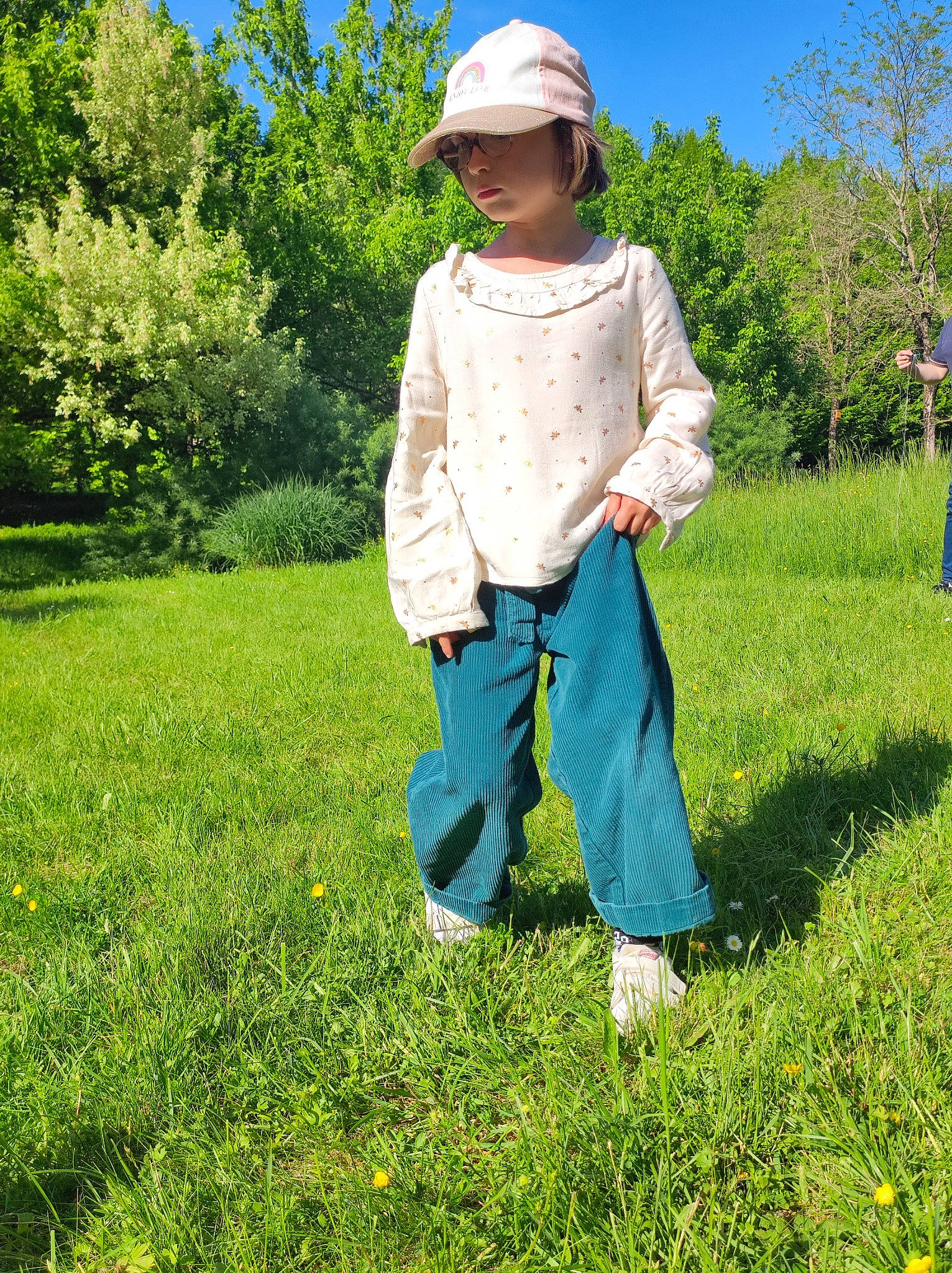 Romane a rejoint le concours — aidez-le/la à gagner de superbes lots ! baby_toddler_clothing, gesture, grass, grass_family, grassland, groundcover, hat, headwear, landscape, leisure, meadow, people_in_nature, person, plant, prairie, shrub, sky, sleeve, sun_hat, toddler