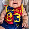 baby, infant, child, smiling, portrait, football_jersey, barcelona, sportswear, red, blue, yellow, play_mat, rainbow, animal_design, monkey, lying_down, indoors, happy, face, bare_feet