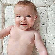 Brooklyn is registered to the contest to win money with this photo: baby, smiling, infant, child, play_mat, patterned_mat, animal_prints, stars, skin, bare_chest, cute, happy, lying_down, young_child, head, face, arm, diaper, indoors, soft_light