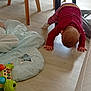 baby, casual_clothing, child, child_playing, crawling, crawling_baby, flooring, furniture_legs, home_interior, hoodie, indoor, leggings, natural_light, play_area, soft_mat, star_mat, toddler, toy, turtle_toy, wooden_floor