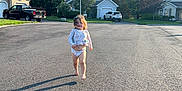 Millie is registered to the contest to win money with this photo: asphalt, barefoot, blue_sky, car, casual_clothing, child, daylight, grass, house, nature, outdoor, person, running, shadow, smiling, street, suburban, sunny, toddler, tree