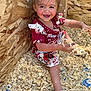 toddler, child, smiling, wood_shavings, play, messy, happy, red_clothing, floral_pattern, shoes, indoors, wooden_wall, fun, cute, young_child, face, arms, legs, sitting, joy