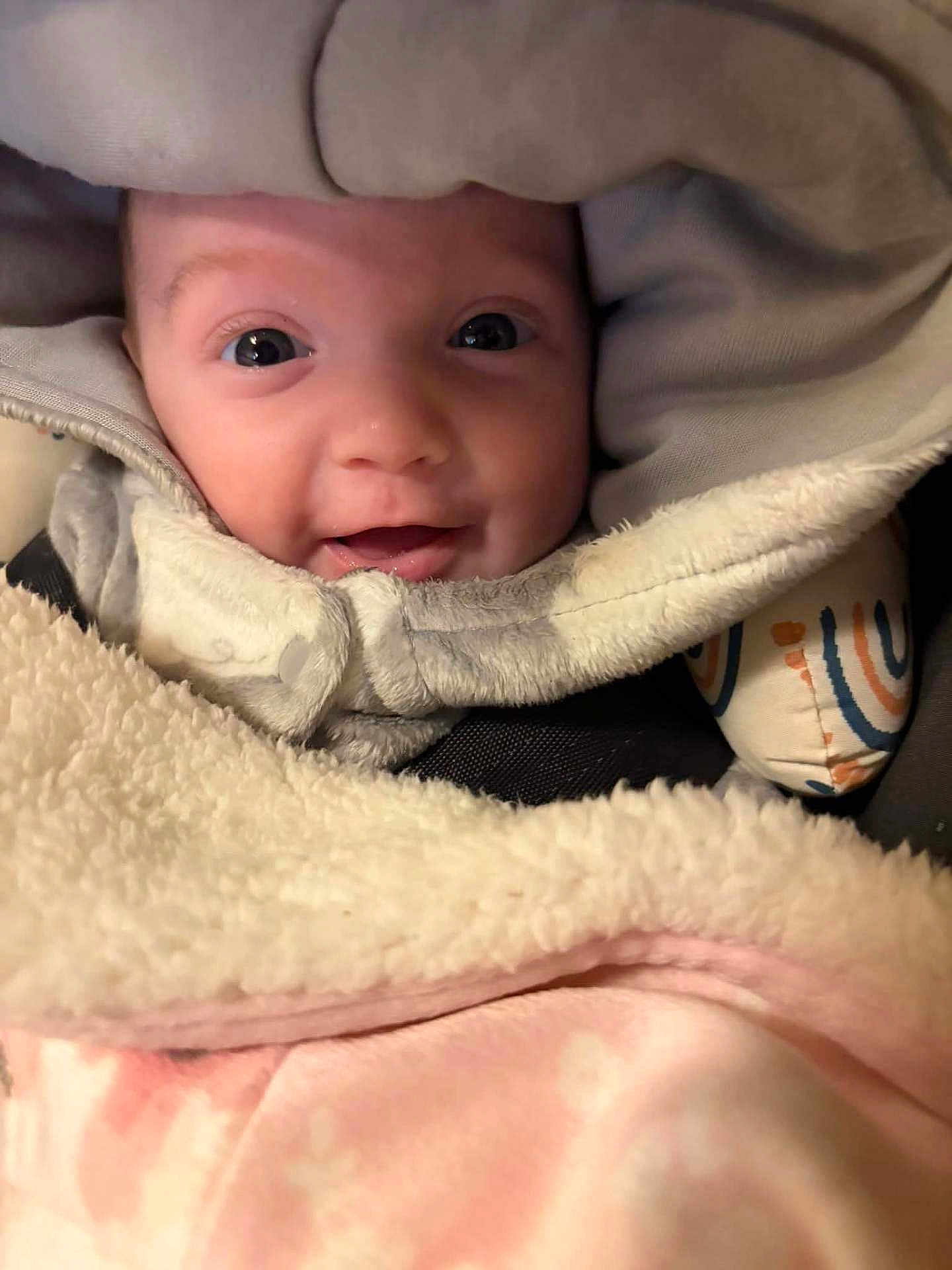 Kelce is registered to the contest to win money with this photo: baby, child, face, smile, hood, blanket, cozy, warm, infant, closeup, cute, happy, apparel, textile, soft, person, portrait, wrapped, indoors, comfort