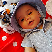 Logan joined the competition — help win amazing prizes! baby, child, infant, hat, clothing, blue_outfit, striped, red_blanket, polka_dot, fleece_blanket, animal_print, baby_bottle, smiling, face, arm, lying_down, indoors, soft_toys, cute, portrait