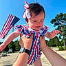 Adalou joined the competition — help win amazing prizes! baby, child, outdoor, blue_sky, american_flag, holding_hands, happy, smiling, bow, dress, person, sunny, daylight, patriotic, cheerful, cute, infant, playing, park, trees