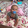 Alora is registered to the contest to win money with this photo: baby, blanket, cabinet, carpet, child, cute, floor, furniture, gray_clothing, hands, head, indoor, infant, pacifier, pattern, pillow, pink, playful, smiling, toy