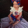 Sabrina is registered to the contest to win money with this photo: baby, child, infant, sitting, wicker_chair, headband, bow, clothing, red, white, blue, stars, stripes, blanket, indoor, curious, person, face, cute, portrait