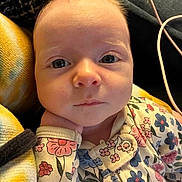 Sabrina is registered to the contest to win money with this photo: baby, infant, face, hand, floral_outfit, eyes, closeup, portrait, cute, child, cozy, soft_lighting, indoors, person, newborn, expression, skin, young, resting, candid