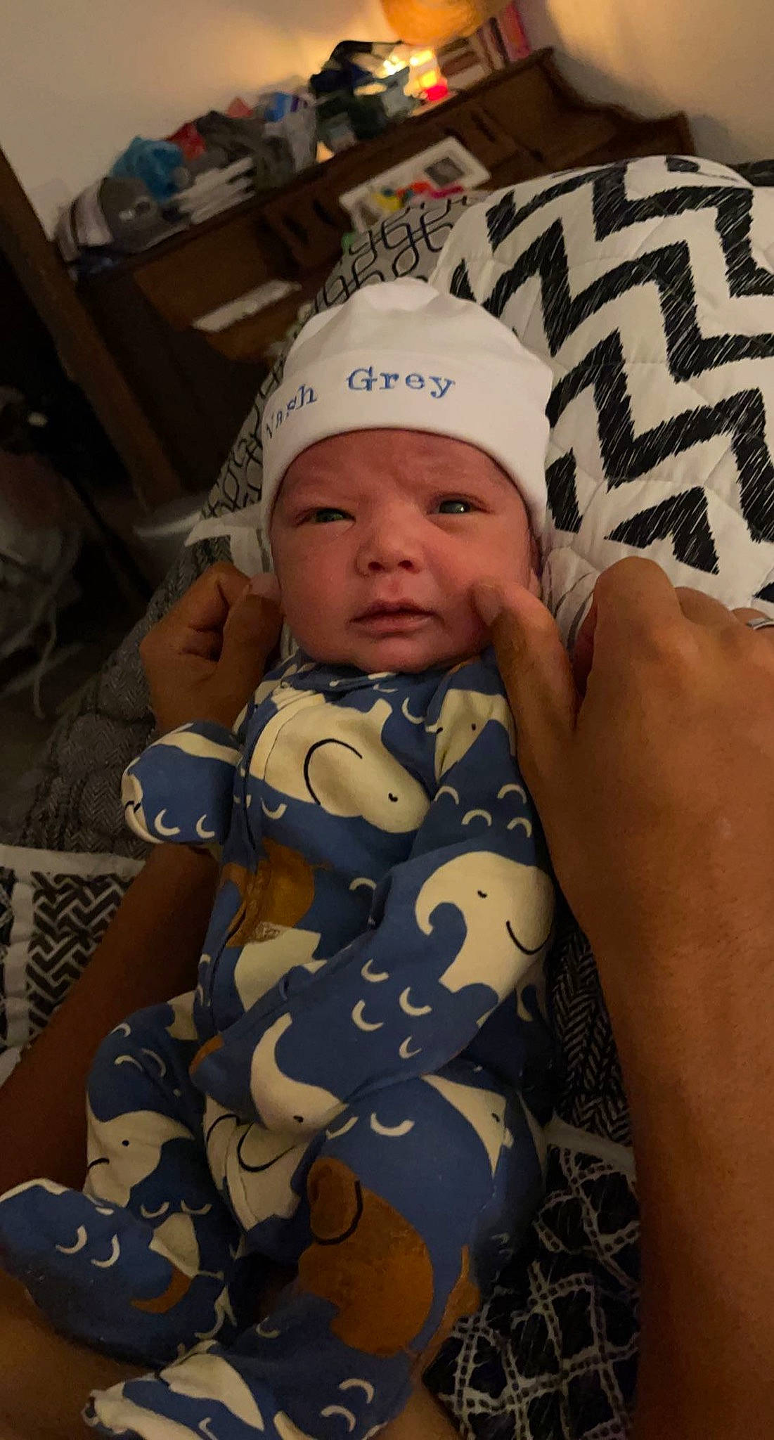 Nash is registered to the contest to win money with this photo: arm, baby, baby_toddler_clothing, cap, cheek, child, comfort, eye, finger, hand, head, headwear, human_body, linens, mouth, pattern, person, skin, sleeve, textile