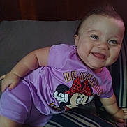 Katlieana is registered to the contest to win money with this photo: baby, child, smiling, purple_clothing, minnie_mouse, bed, bedding, striped, headboard, happy, infant, person, indoors, cute, portrait, toddler, short_sleeves, lying_down, face, cheerful