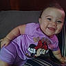 baby, child, smiling, purple_clothing, minnie_mouse, bed, bedding, striped, headboard, happy, infant, person, indoors, cute, portrait, toddler, short_sleeves, lying_down, face, cheerful