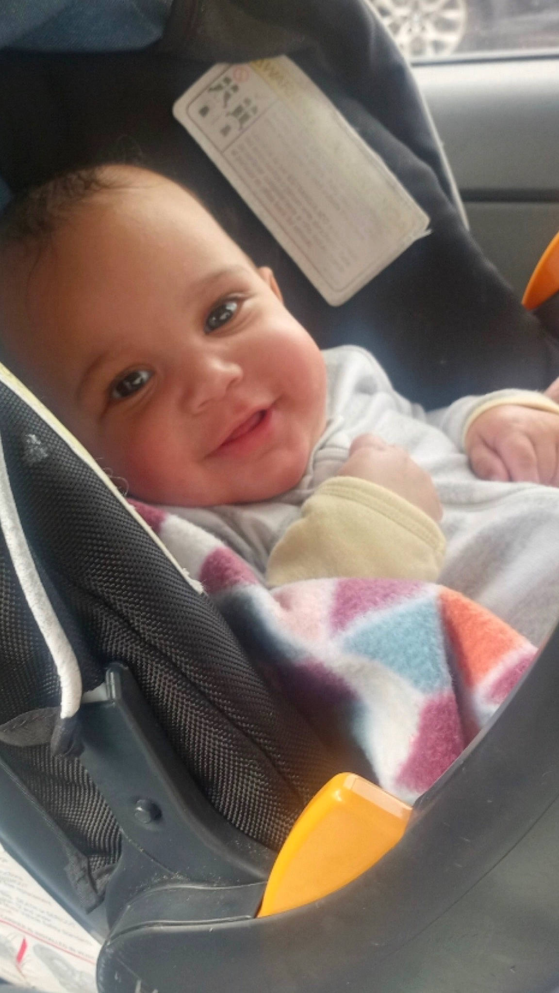 Sophia is registered to the contest to win money with this photo: auto_part, baby, baby_carriage, baby_in_car_seat, baby_products, baby_safety, baby_toddler_clothing, car_seat, cheek, child, comfort, happy, lap, linens, person, sitting, smile, toddler