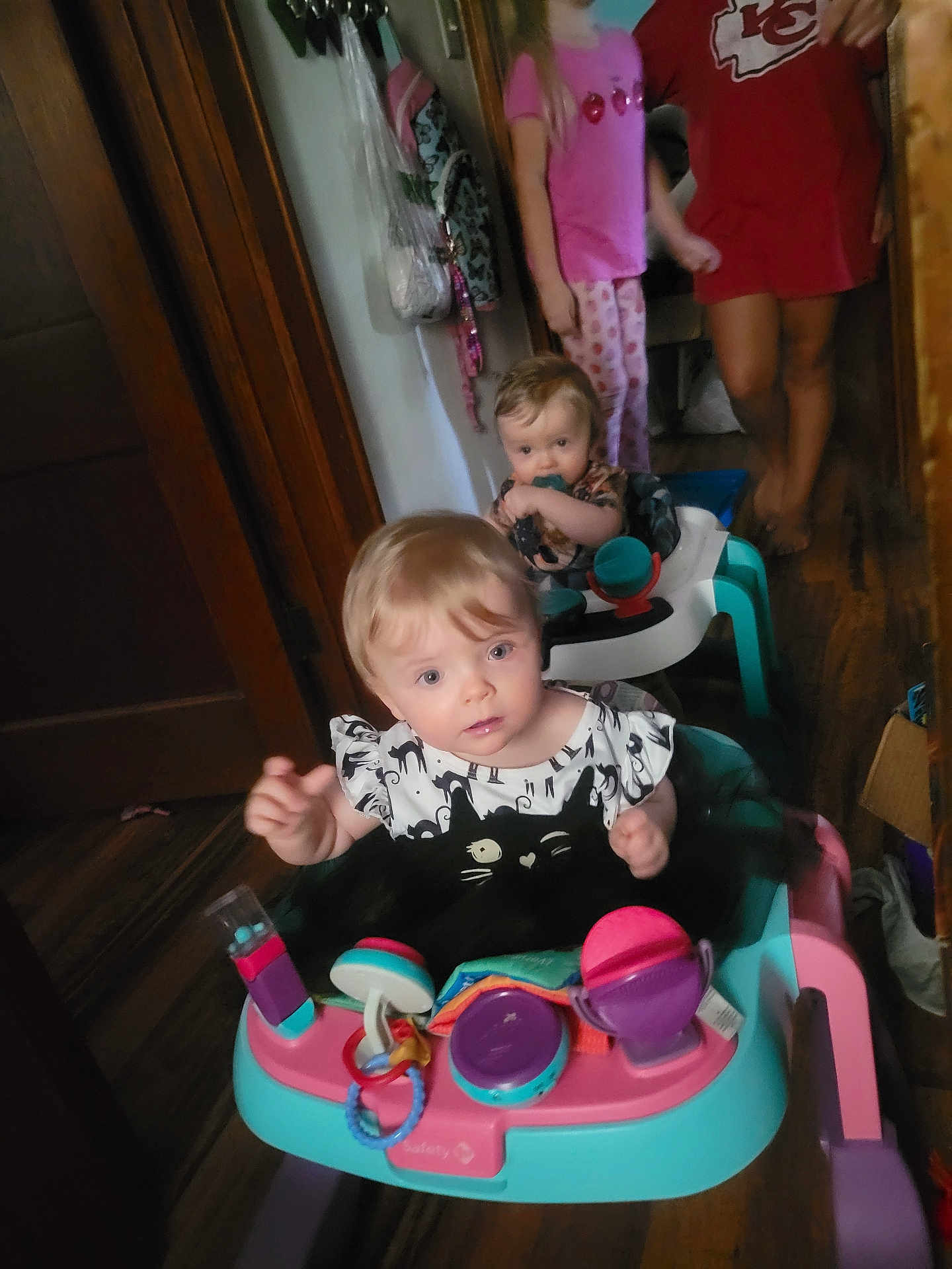 Harlyn joined the competition — help win amazing prizes! baby, toddler, walker, indoor, child, toy, floor, wood, person, clothing, pacifier, curly_hair, pink, blue, black_and_white, family, hallway, blurred_background, standing, play