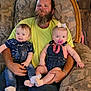 man, beard, baby, infant, child, overalls, pacifier, bow, socks, couch, armchair, smile, happy, indoor, family, person, clothing, seated, wood_floor, bracelet