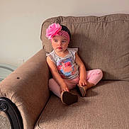 Isamar joined the competition — help win amazing prizes! carpet, casual_clothing, child, couch, cute, flower, furniture, girl, headband, home, indoors, living_room, pants, pink, portrait, relaxed, seated, shirt, small_person, young_child