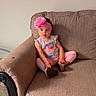 carpet, casual_clothing, child, couch, cute, flower, furniture, girl, headband, home, indoors, living_room, pants, pink, portrait, relaxed, seated, shirt, small_person, young_child