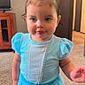 blue_dress, bow, cabinet, carpet, child, closeup, curly_hair, cute, fashion, furniture, girl, happy, indoor, person, portrait, room, smile, standing, toddler, young_child