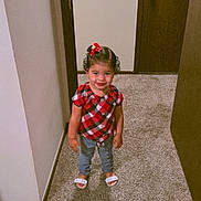 Isamar Victoria is registered to the contest to win money with this photo: child, girl, smiling, standing, plaid_shirt, red_bow, curly_hair, sandals, carpet, hallway, door, wall, indoor, person, cute, happy, young_child, fashion, home, portrait