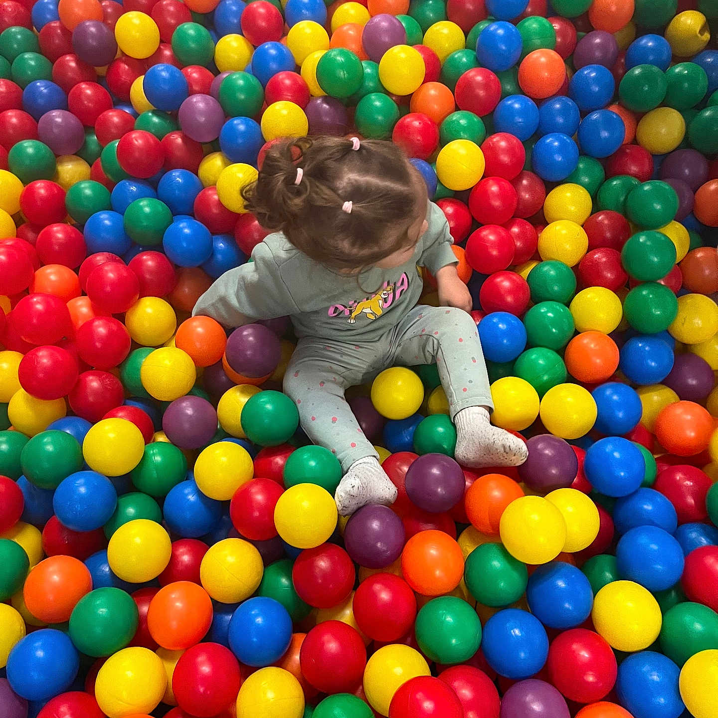 Talia a rejoint le concours — aidez-le/la à gagner de superbes lots ! ball_pit, casual_clothing, child, childhood, colorful_balls, fun, hair, indoor, leisure, pigtails, plastic_balls, play, play_area, portrait, sitting, socks, toddler, top_view, toy, vibrant_colors