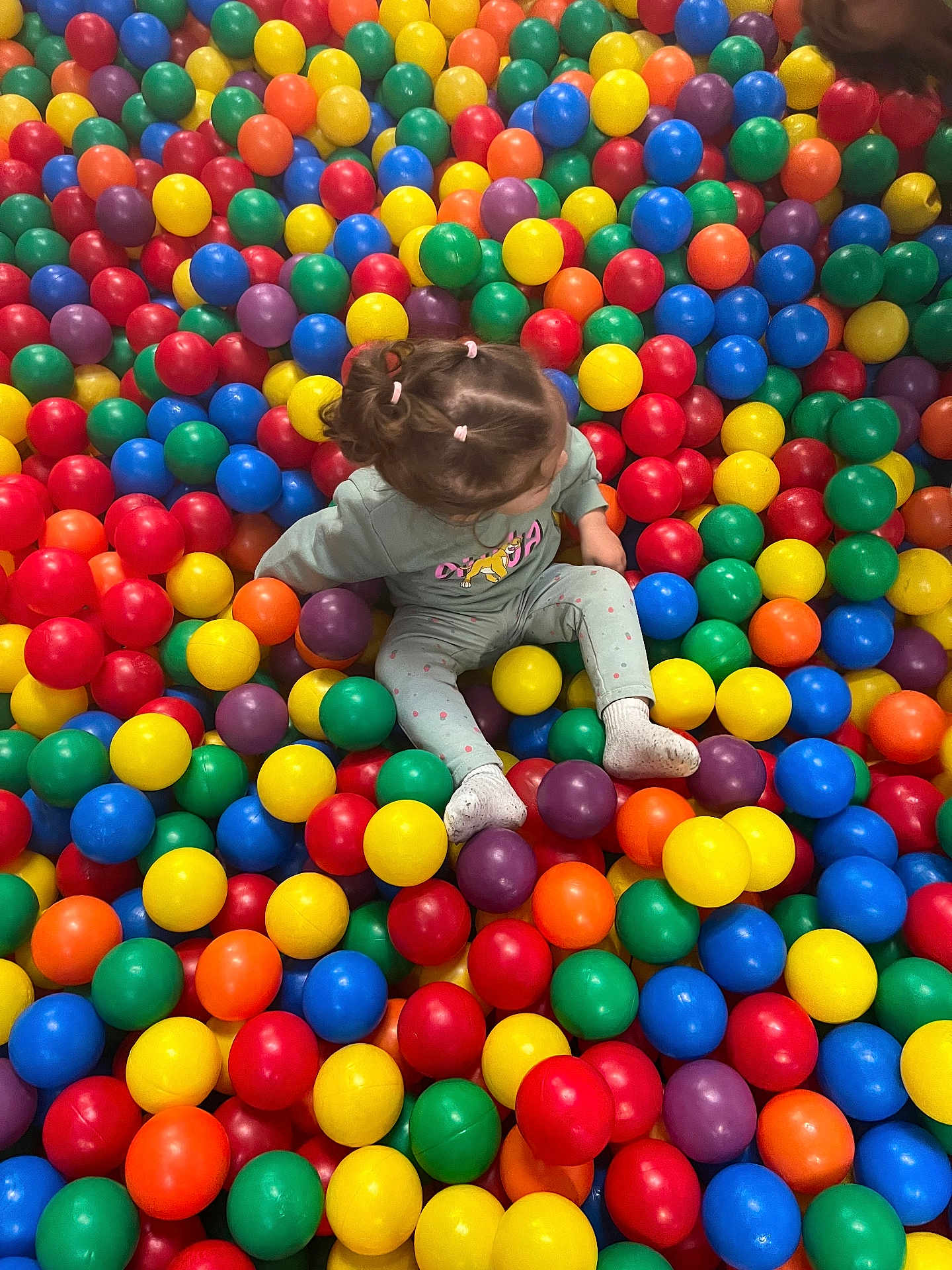 Talia a rejoint le concours — aidez-le/la à gagner de superbes lots ! ball_pit, casual_clothing, child, childhood, colorful_balls, fun, hair, indoor, leisure, pigtails, plastic_balls, play, play_area, portrait, sitting, socks, toddler, top_view, toy, vibrant_colors
