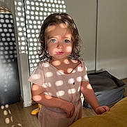 Talia a rejoint le concours — aidez-le/la à gagner de superbes lots ! toddler, child, indoor, sunlight, shadow_pattern, curly_hair, pink_clothing, face, portrait, wooden_floor, soft_light, cute, person, standing, expression, home_interior, wall, floor, playful_light, casual_clothing