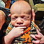baby, infant, hand, fingers, clothing, camouflage, orange, person, indoor, newborn, face, expression, cute, skin, sleeping, closeup, holding, adult_hand, portrait, child