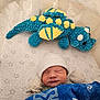 Alexander is registered to the contest to win money with this photo: baby, newborn, sleeping, crib, blanket, mittens, hat, plush_toy, dinosaur_toy, star_pattern, bedding, infant, cozy, child, soft_toy, sleep, cute, baby_clothing, indoor, resting