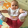 Chloé participe au concours pour gagner de l'argent avec cette photo : baby, infant, child, play_mat, colorful, feet, holding_feet, socks, bib, pink_clothing, smiling, cute, indoor, floor, animal_illustrations, measurement_scale, happy, young_child, person, portrait