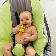 Chloé a rejoint le concours — aidez-le/la à gagner de superbes lots ! baby, infant, teething_toy, smiling, chubby, blue_eyes, baby_bouncer, green, gray, indoor, floor, happy, cute, child, person, plush, fun, skin, diaper, toy