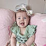Rose a rejoint le concours — aidez-le/la à gagner de superbes lots ! adorable, baby, blue_eyes, bow, child, clothing, cute, floral_skirt, green_top, happy, headband, indoors, infant, person, pink_cushion, portrait, sitting, smiling, soft_texture, young_child