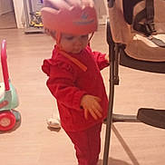 Rose participe au concours pour gagner de l'argent avec cette photo : baby, chair, child, cushion, floor, footwear, furniture, helmet, helmet_strap, home, indoor, living_room, person, play, red_clothing, shadow, standing, television, toddler, toy