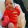 baby, newborn, infant, onesie, red_clothing, blanket, soft_texture, lying_down, cute, face, expression, hand, foot, indoors, person, child, sleepwear, portrait, resting, cozy