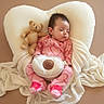 baby, sleeping, teddy_bear, heart_pillow, pink_pajamas, footed_pajamas, blanket, soft_toys, infant, cozy, cute, resting, child, adorable, indoor, comfort, peaceful, portrait, head, clothing