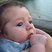 Oliver is registered to the contest to win money with this photo: baby, closeup, face, blue_eyes, hand, infant, skin, person, outdoor, nature, portrait, cute, young, child, holding, expression, soft_light, natural_background, human, newborn