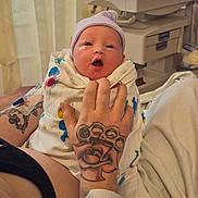 Whitley is registered to the contest to win money with this photo: newborn, baby, hospital, tattoo, hand, hospital_wristband, blanket, hat, medical_equipment, patient, infant, bed, curtain, person, skin, face, crying, resting, care, healthcare